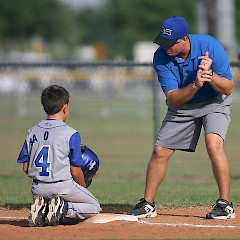 Lapsi kuuntelee polvillaan valmentajan näyttäessä oikeaa baseball-lyöntiasentoa